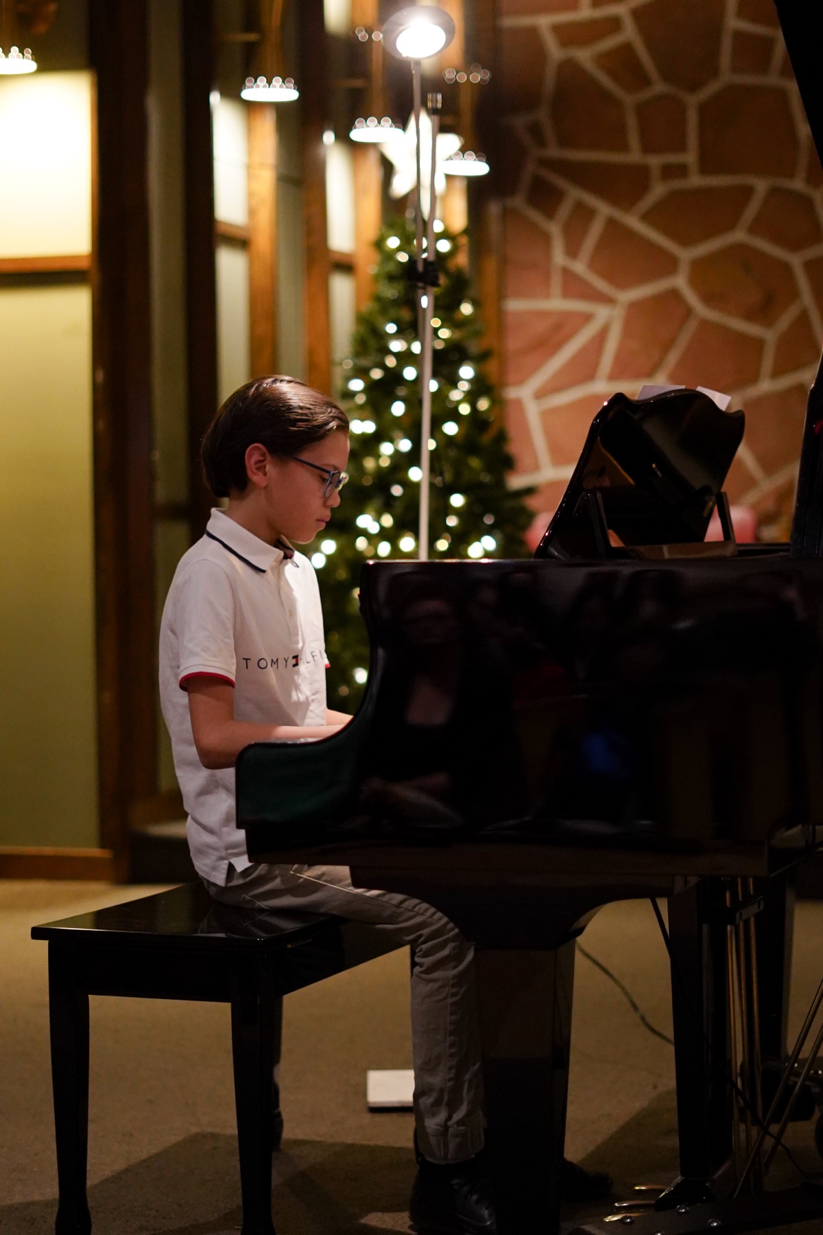 Un jeune pianiste avec des lunettes joue du piano à queue sur scène